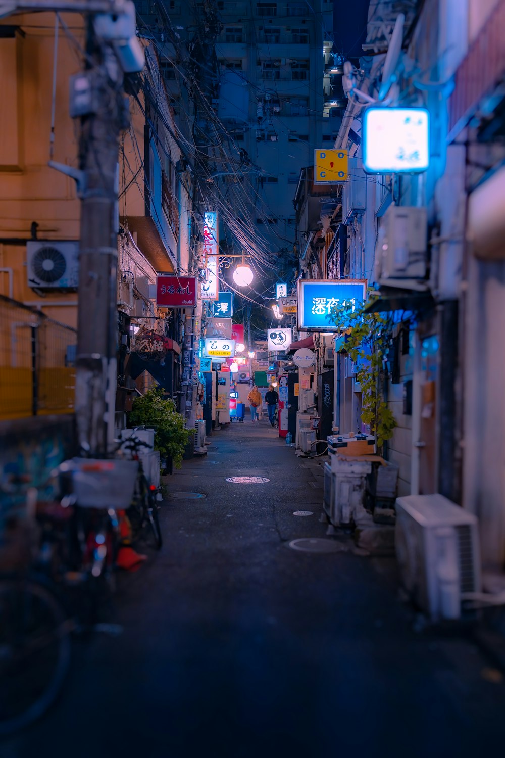 a narrow city street at night with neon signs