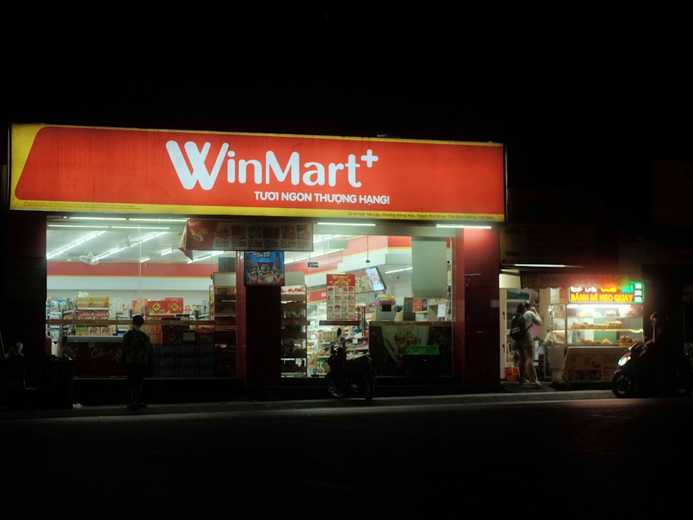 a store front at night with people walking by