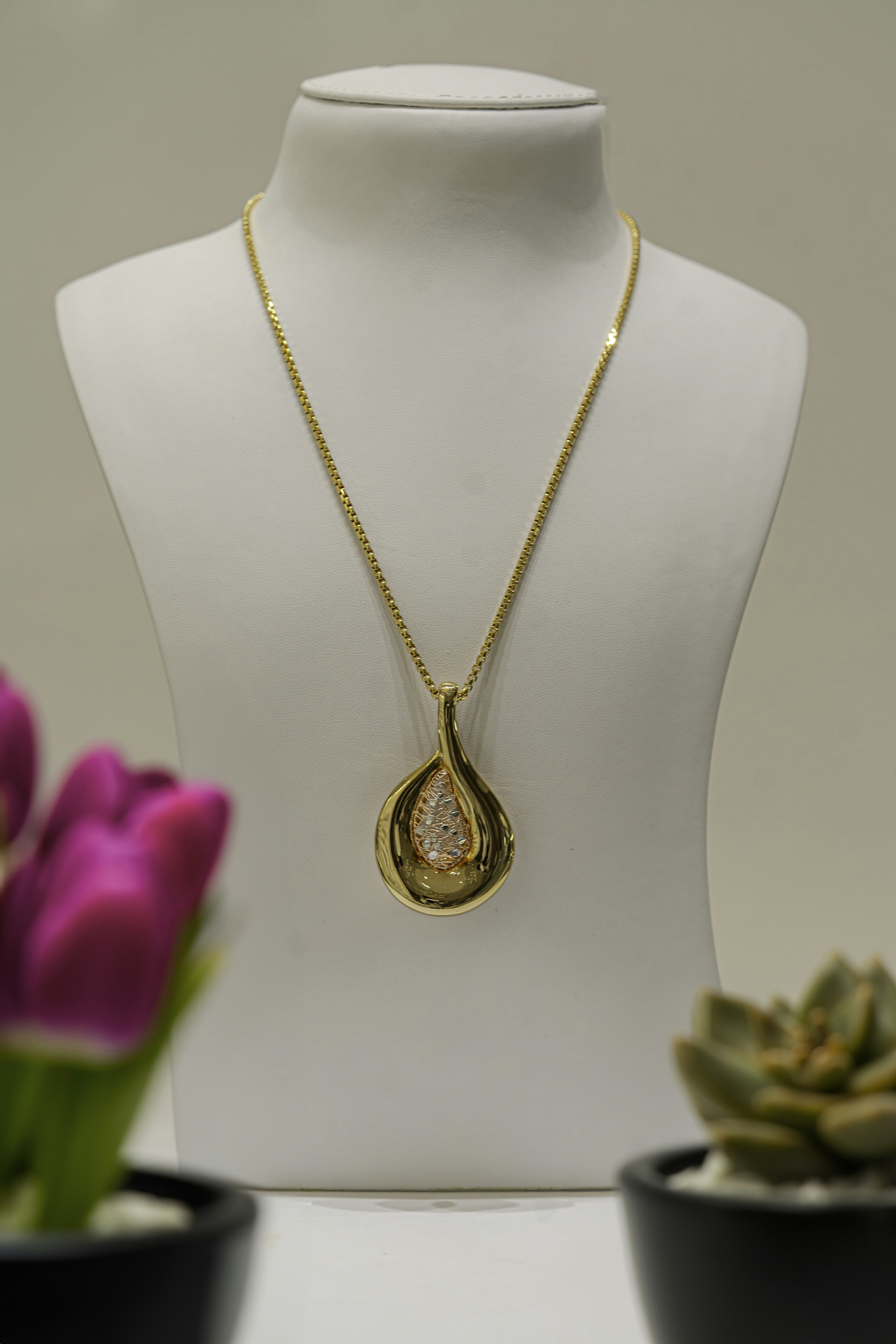 a necklace on a mannequin with flowers in the background
