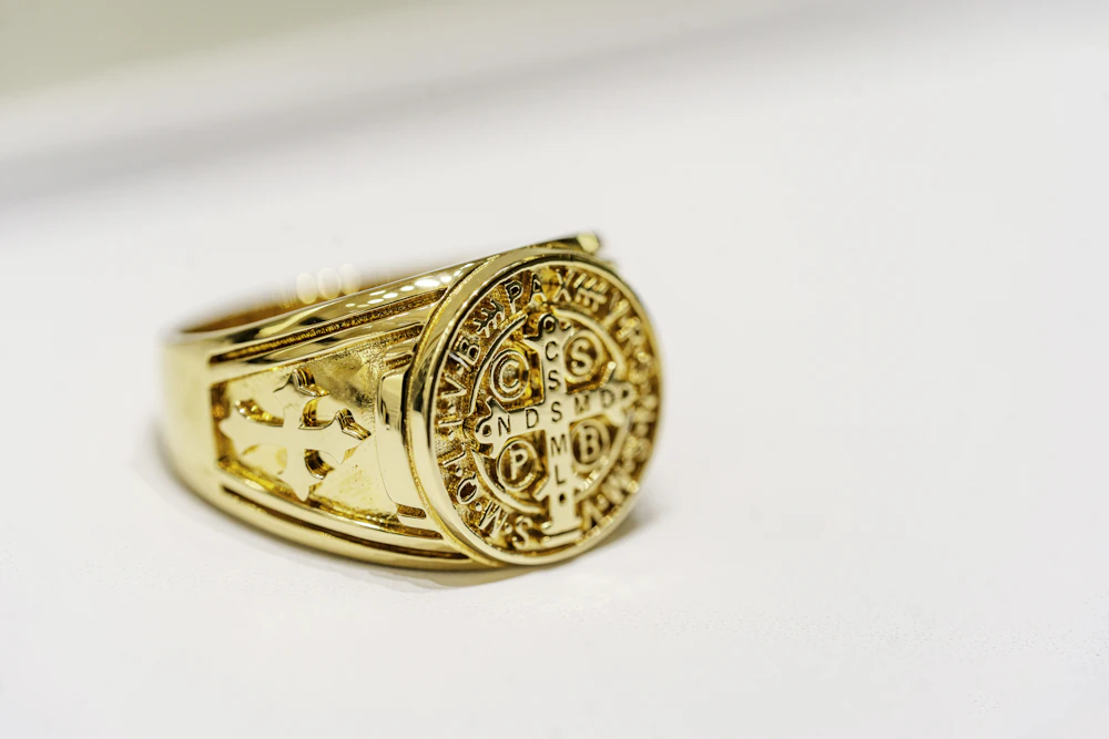 Engraved gold signet ring on a white surface