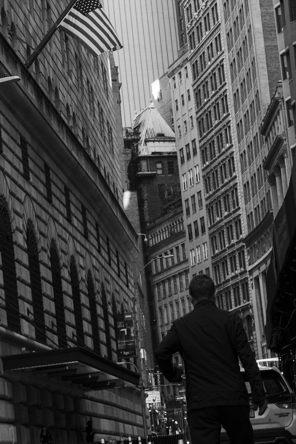 a man walking down a street next to tall buildings