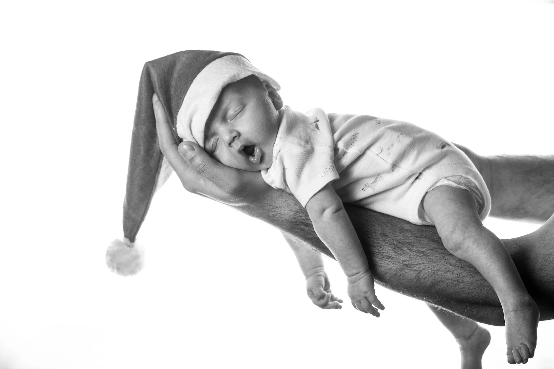 a man holding a baby wearing a santa hat
