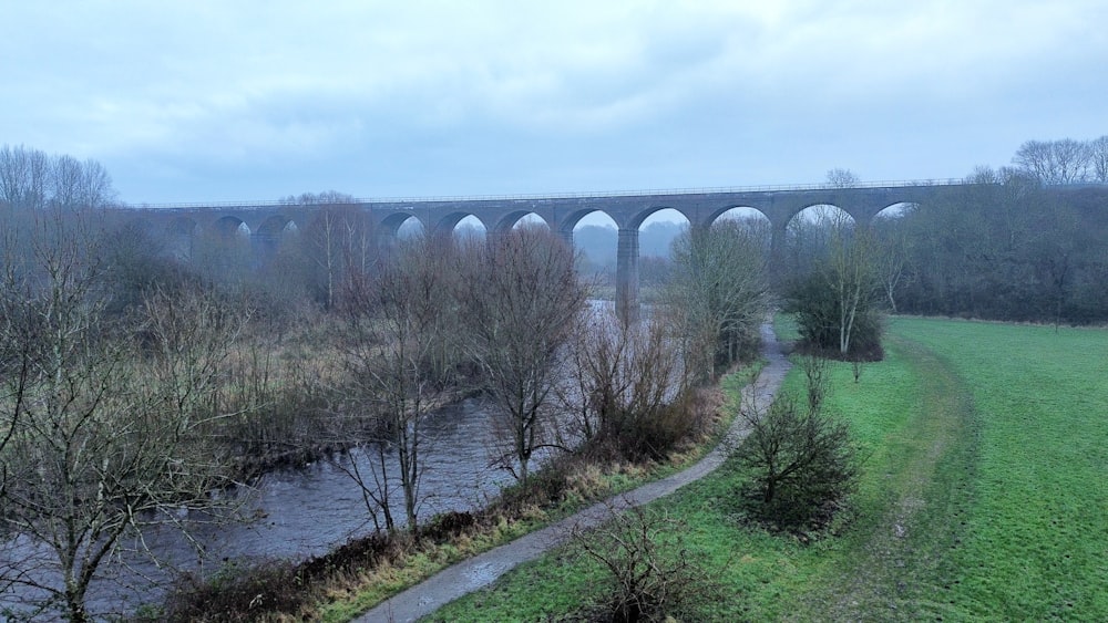 a bridge over a river next to a lush green field