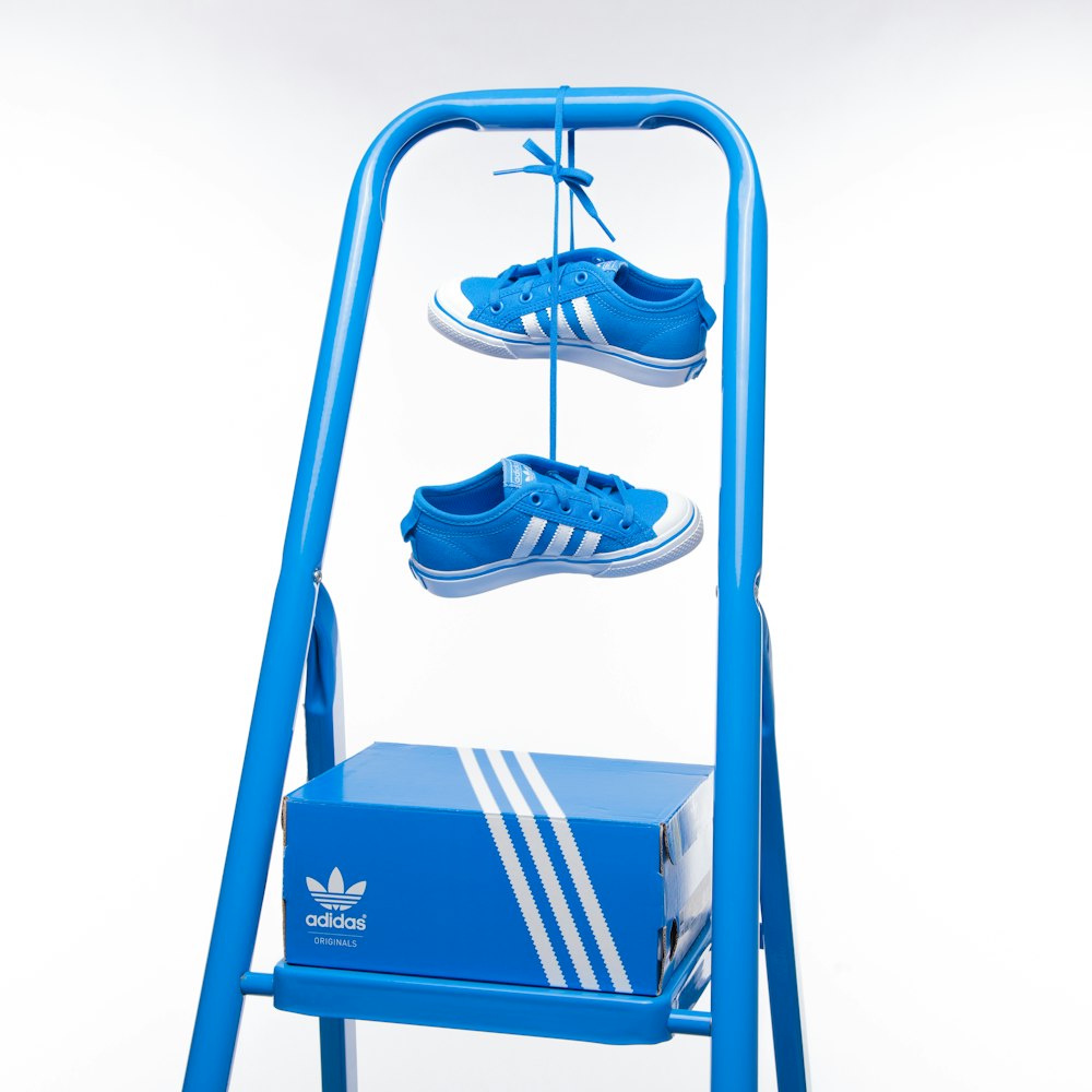 a blue adidas shoe rack with three pairs of shoes on it
