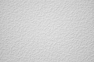 a white textured wall with a small amount of paint on it