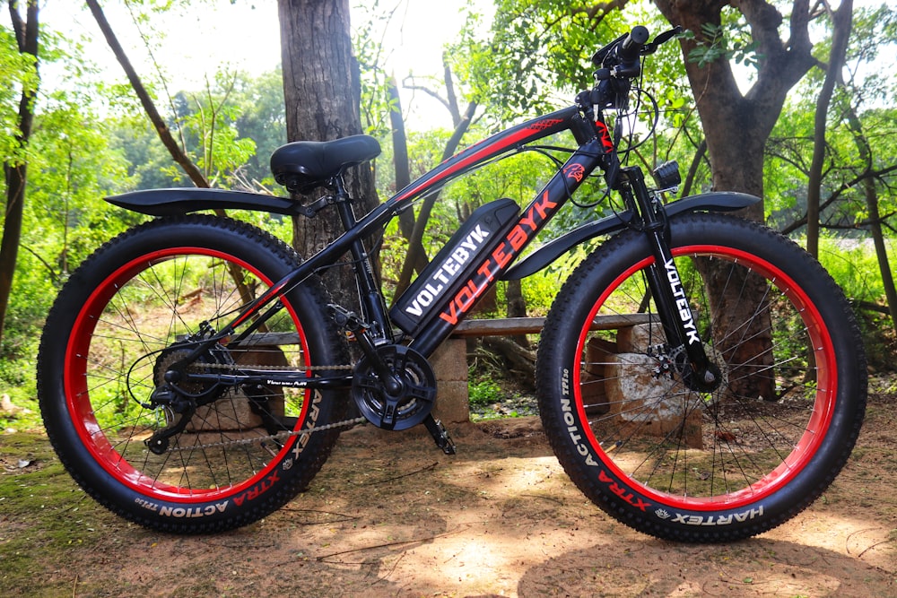 a black and red bike parked in a wooded area