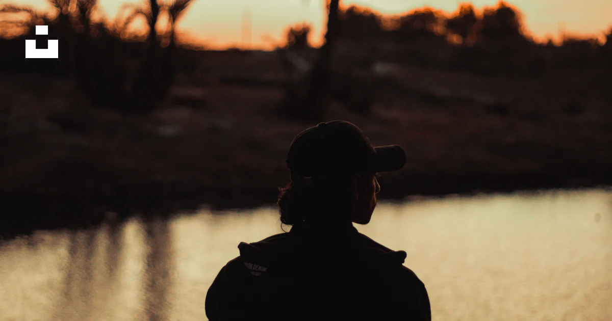 A person standing in front of a body of water photo – Free Backlighting ...