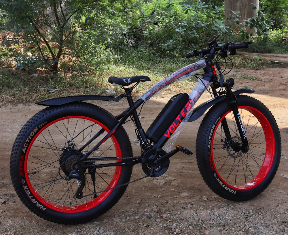 a bicycle with red rims parked on a dirt road