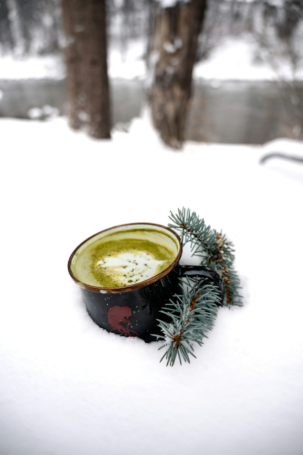 a cup of coffee sitting on top of a snow covered ground