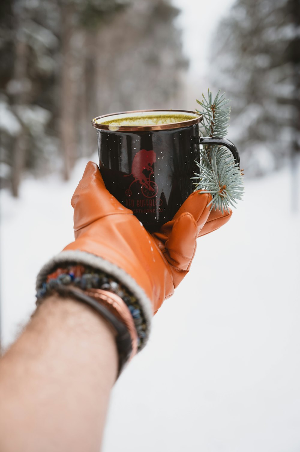 a hand holding a cup of coffee in the snow