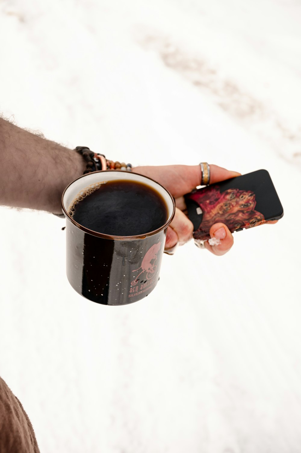 una persona che tiene in mano una tazza di caffè e un telefono cellulare