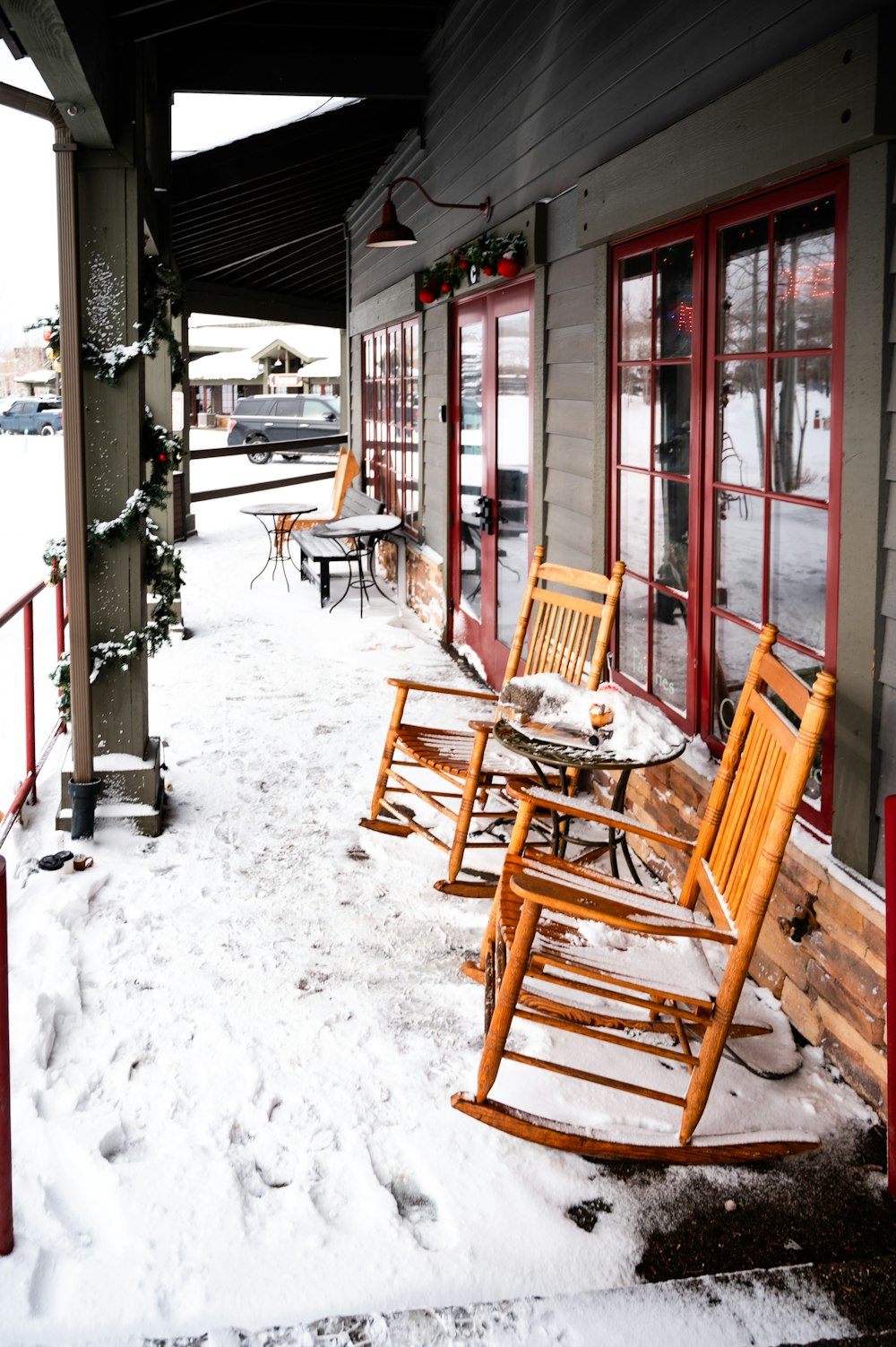a couple of wooden rocking chairs sitting on top of a snow covered sidewalk