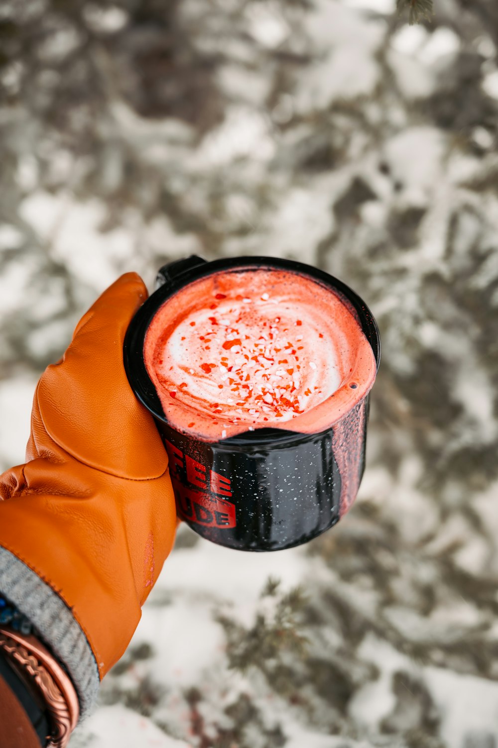 a person holding a drink in their hand in the snow