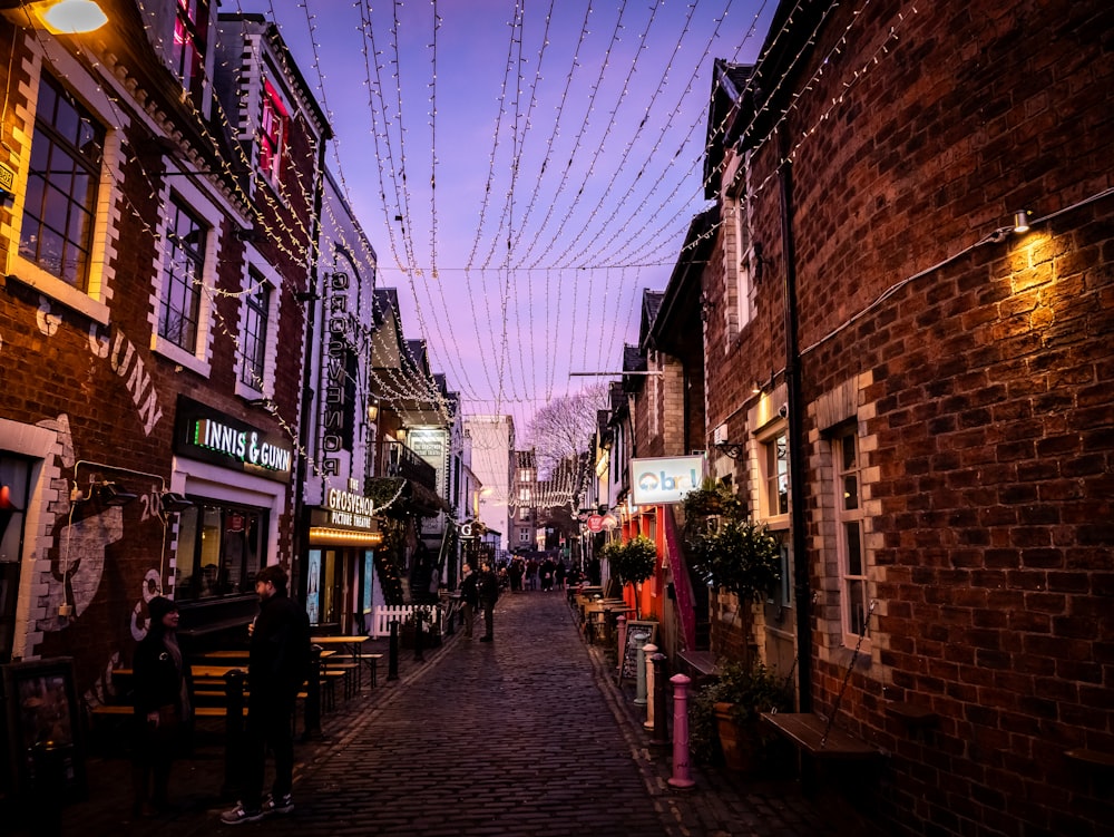 a city street lined with brick buildings and string lights