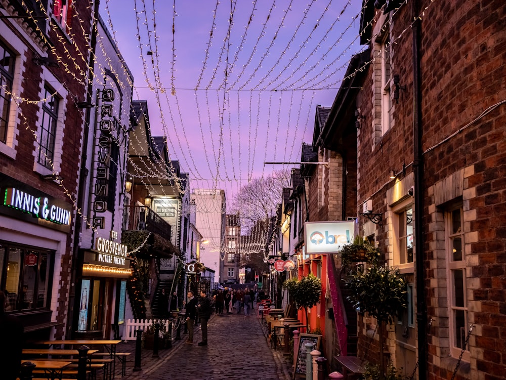a city street lined with brick buildings and string lights