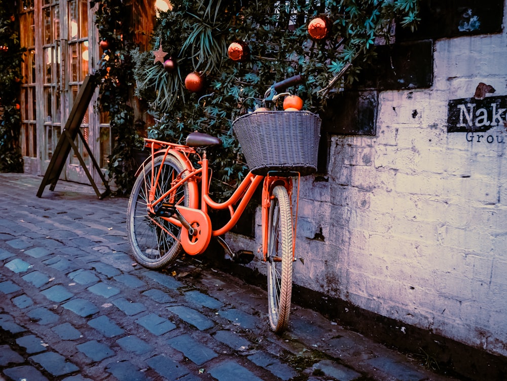 an orange bicycle parked next to a white brick wall