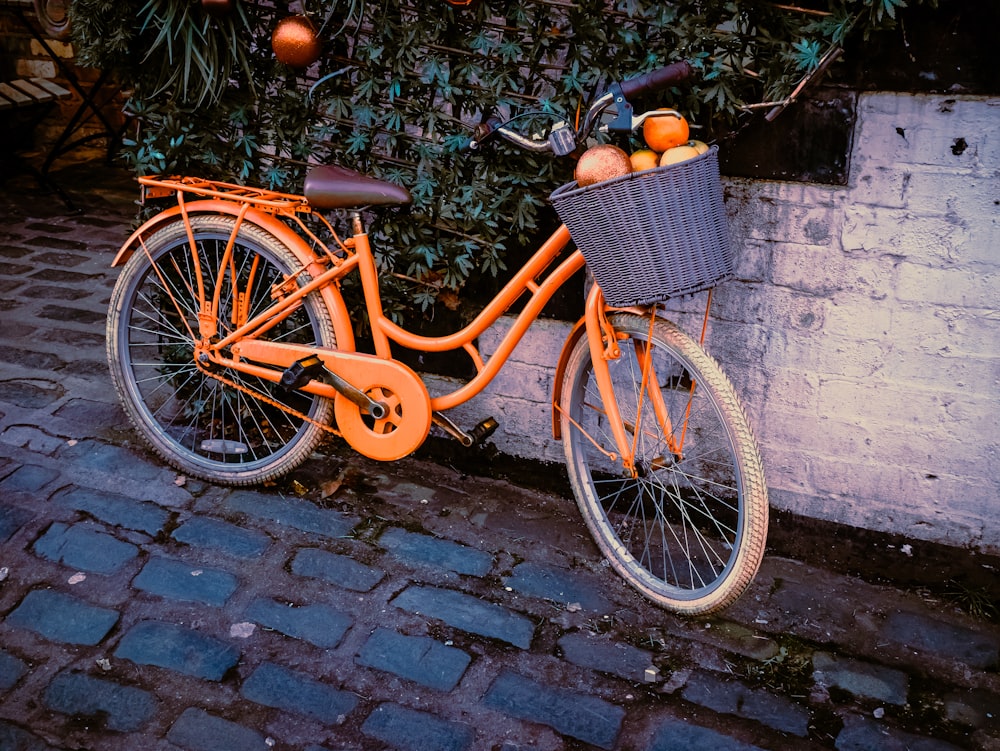 an orange bicycle parked next to a white brick wall