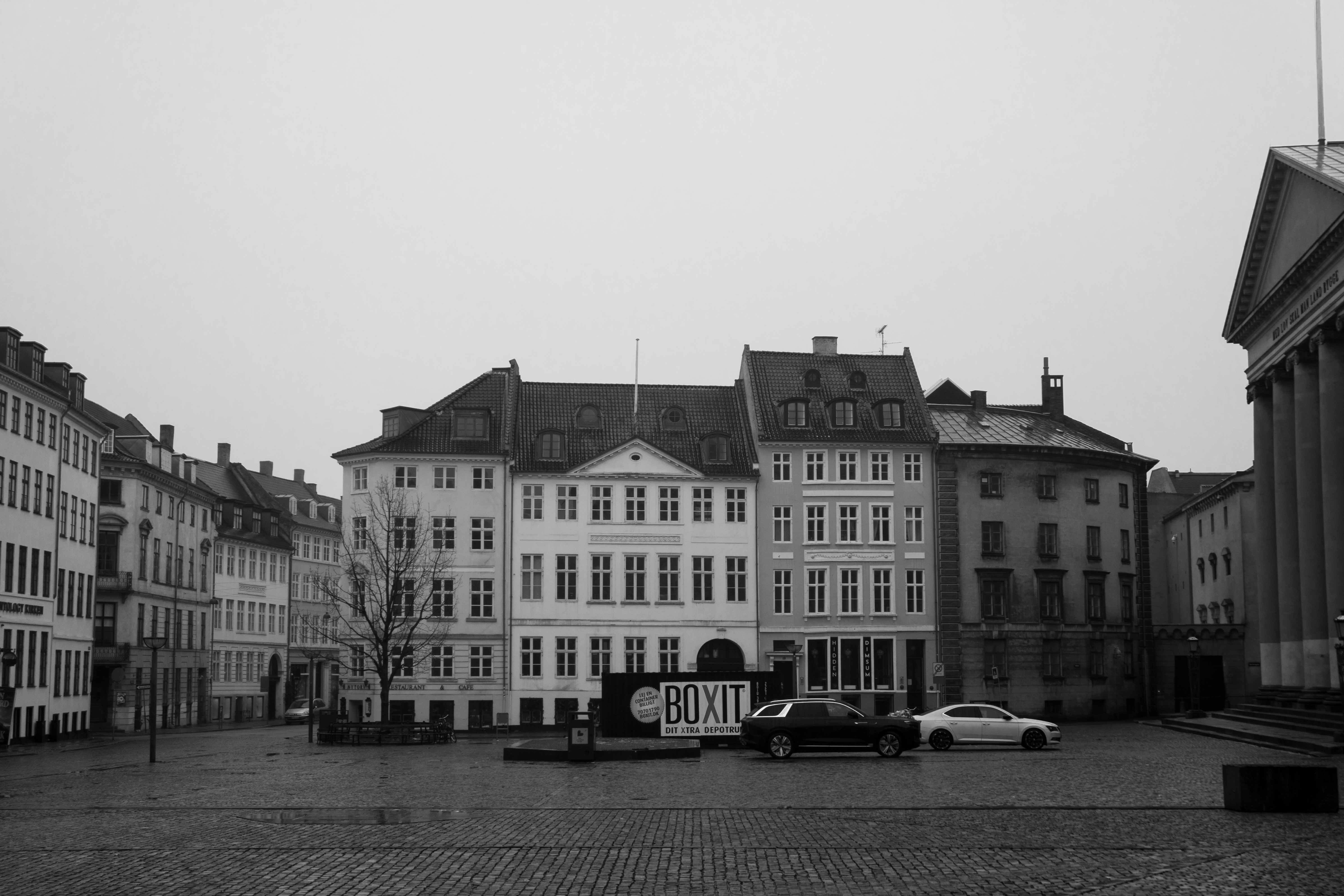 Cars parked on a cobblestone square in front of historic buildings in Copenhagen