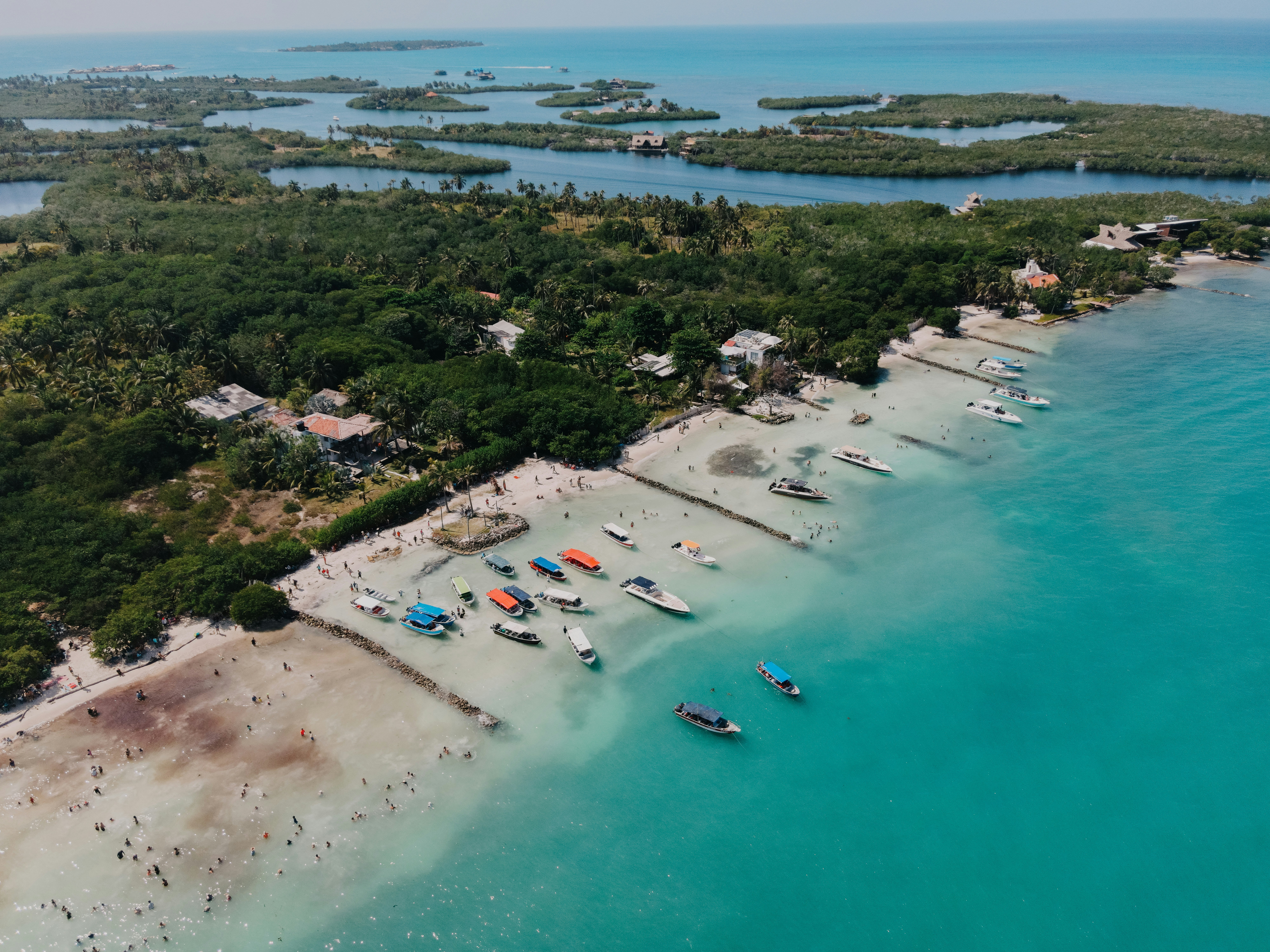 an aerial view of a beach with boats in the water, 