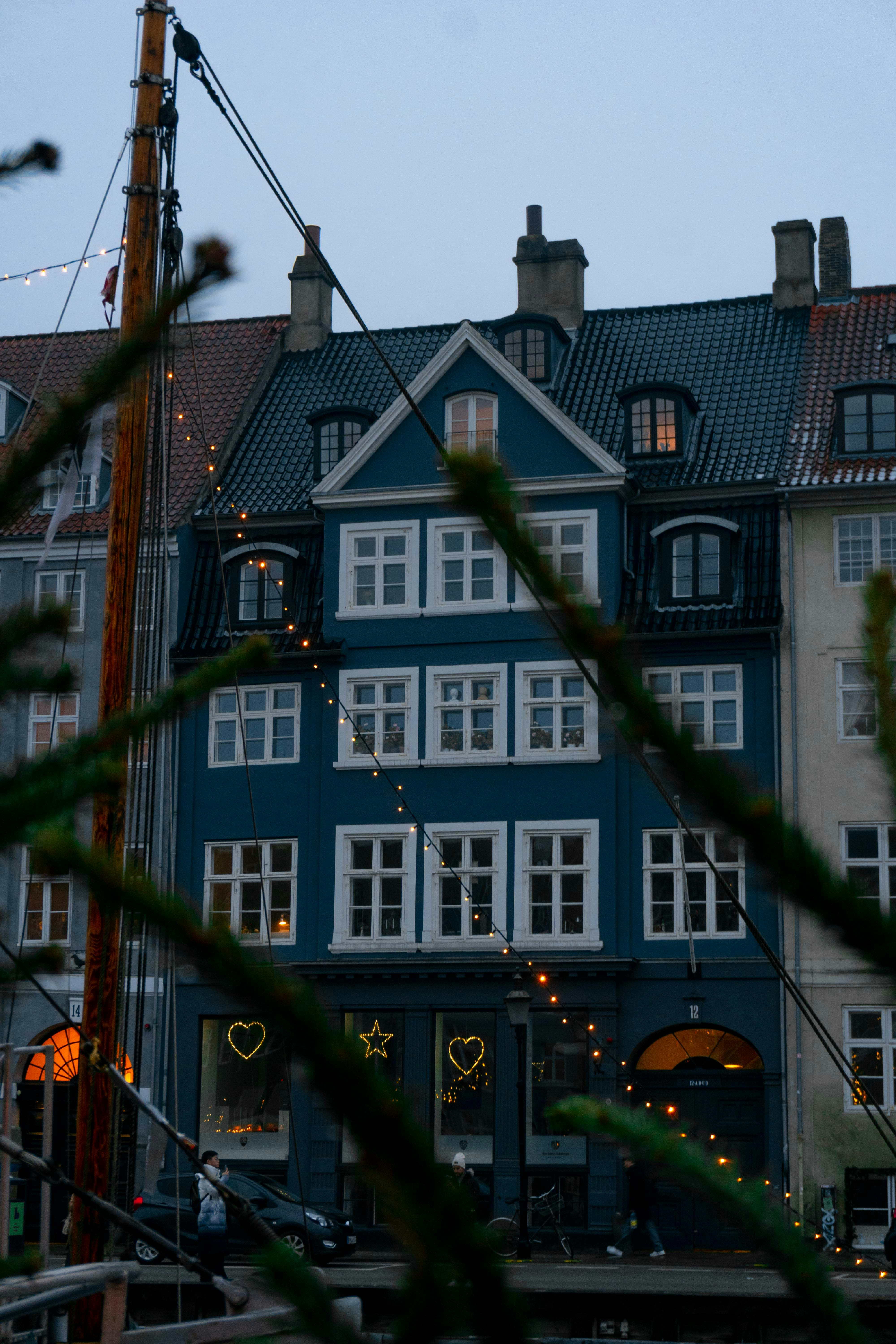 A blue building with white window frames and festive heart and star lights
