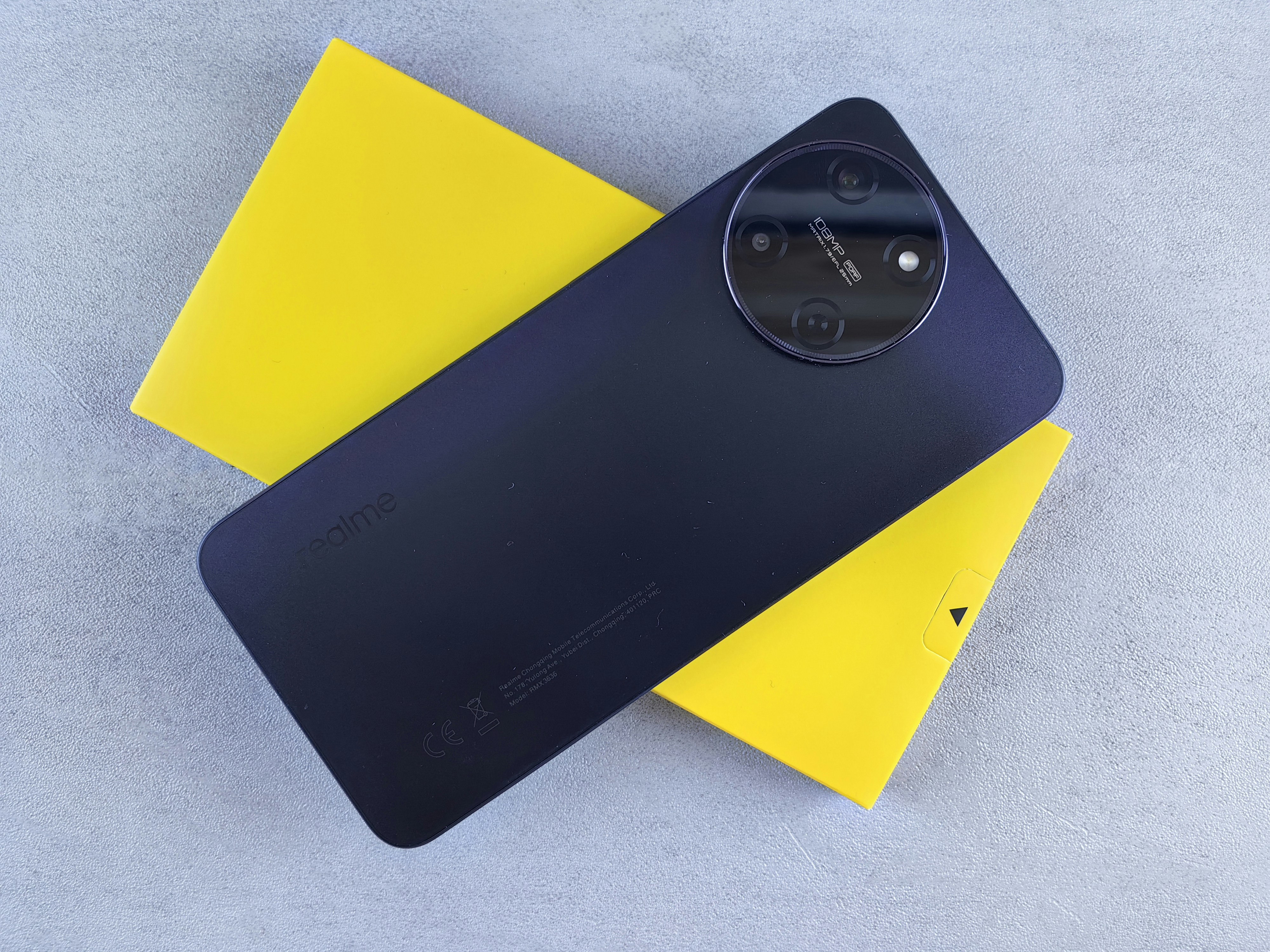 Gold Realme smartphone on reflective surface with bright studio lighting