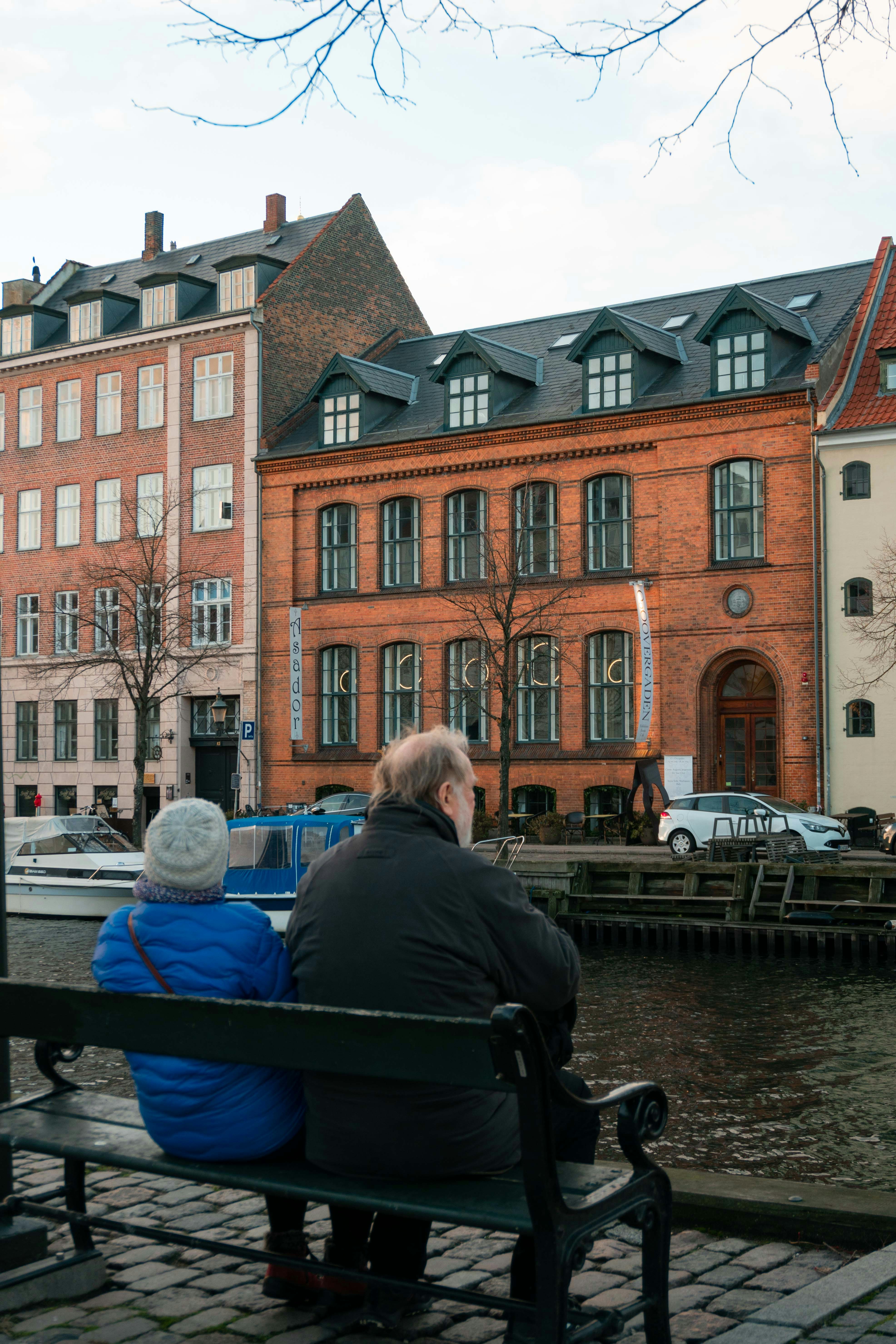Two people sitting on a bench by a canal in Copenhagen
