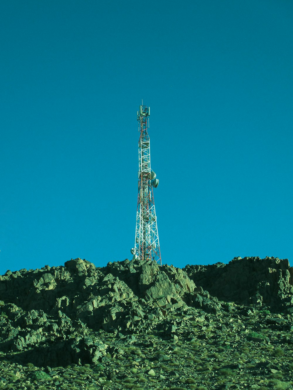 uma torre de rádio no topo de uma colina rochosa
