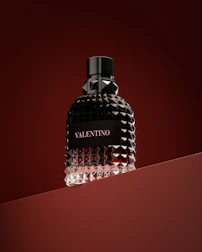 a bottle of perfume sitting on top of a red surface