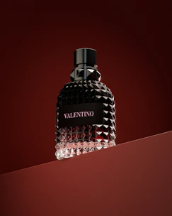 a bottle of perfume sitting on top of a red surface
