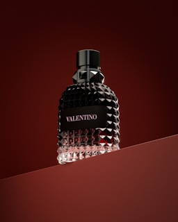 a bottle of perfume sitting on top of a red surface