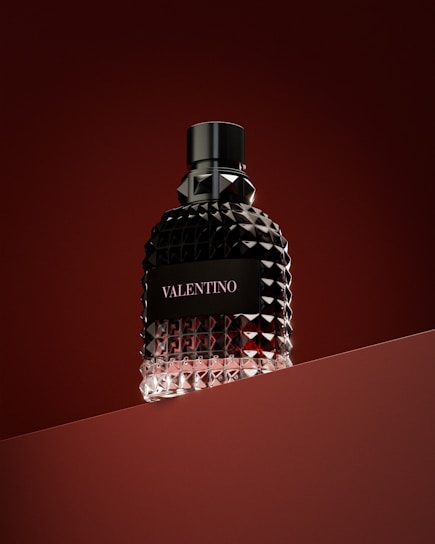 a bottle of perfume sitting on top of a red surface