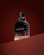 a bottle of perfume sitting on top of a red surface