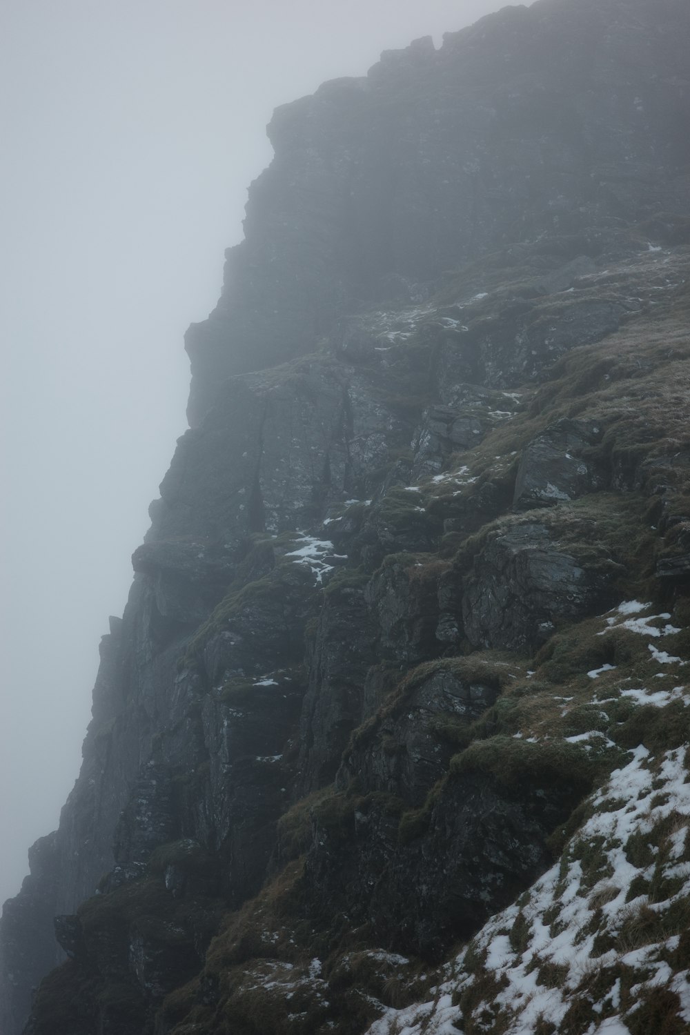 a foggy mountain side with a person standing at the top