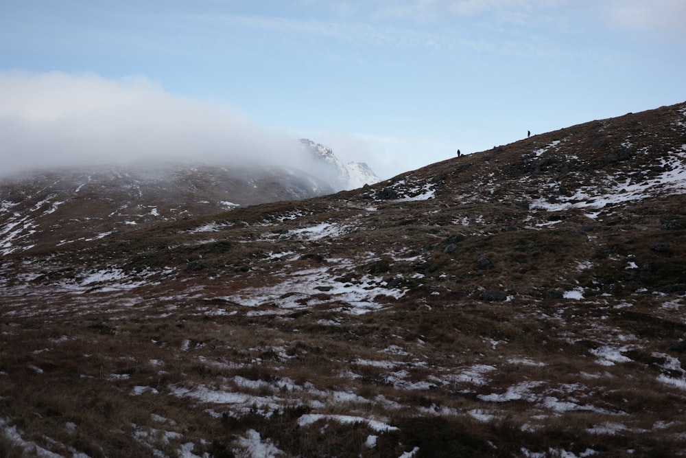 a hill covered in snow and fog with a person standing on top of it