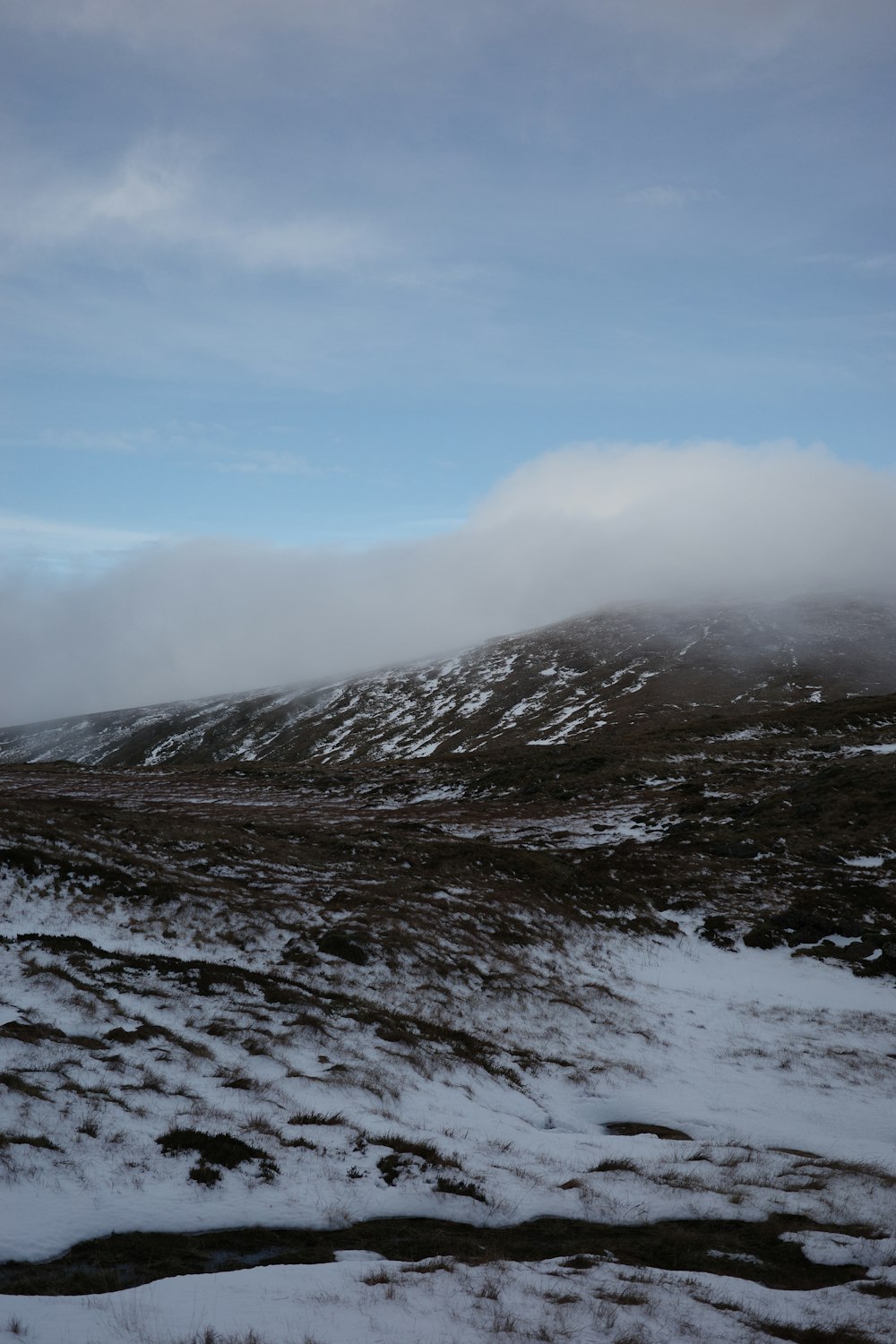 a hill covered in snow under a cloudy sky