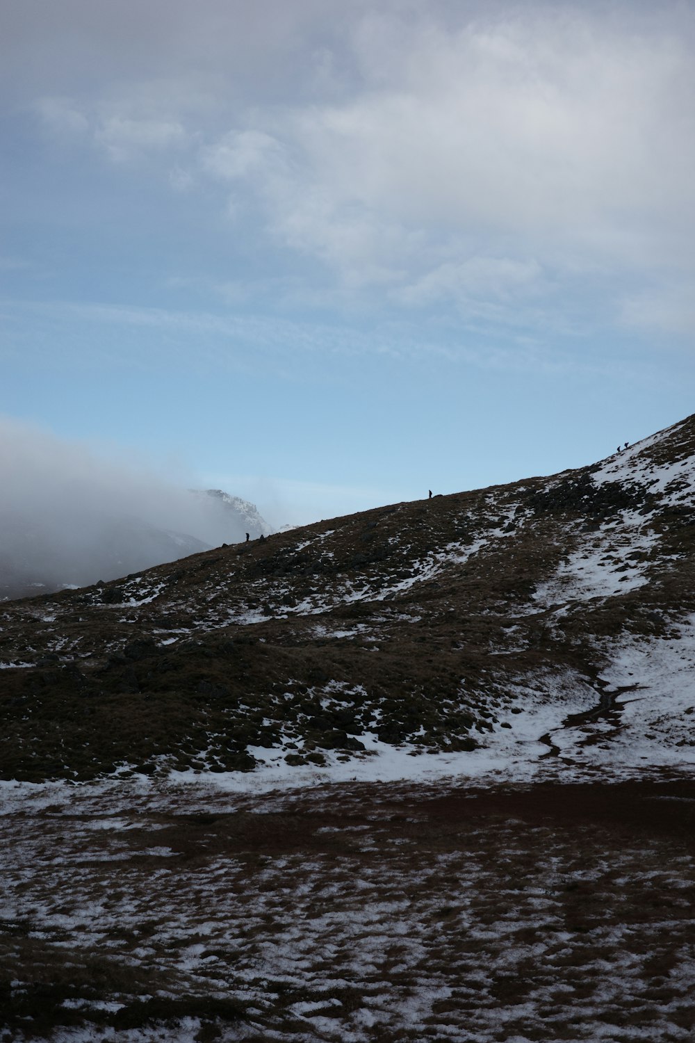 a hill covered in snow under a cloudy sky