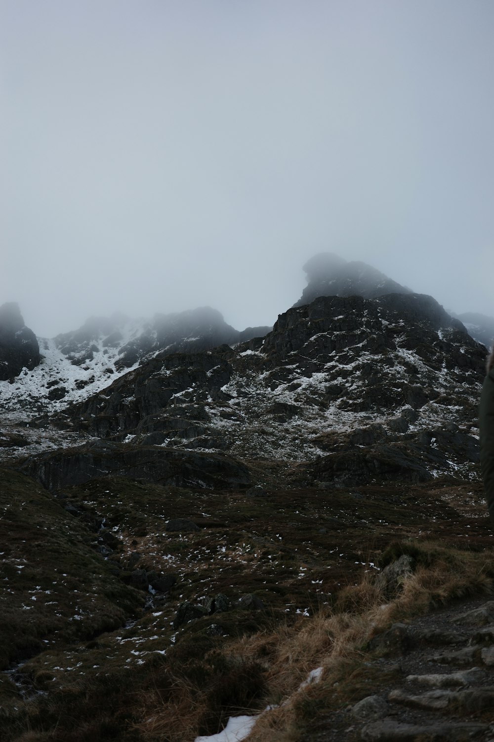 a person standing on a rocky hill with snow on it