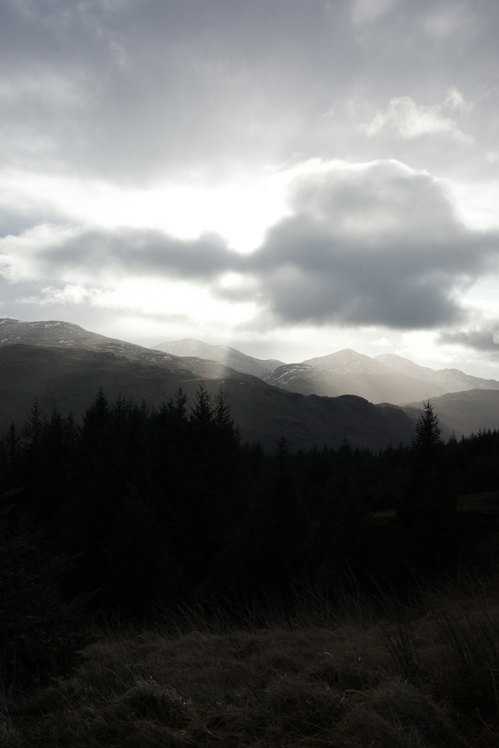 the sun is shining through the clouds over the mountains