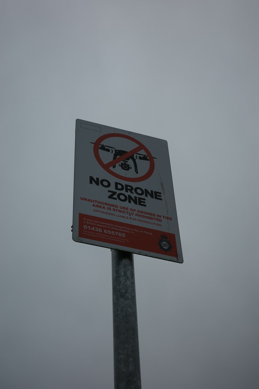 a no drone zone sign on a pole