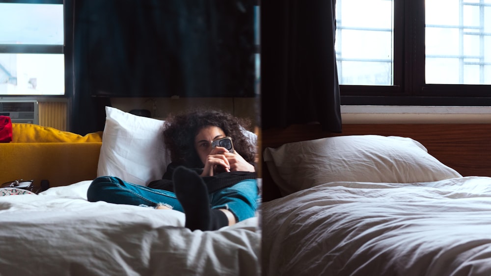 a woman laying on a bed taking a picture of herself in a mirror