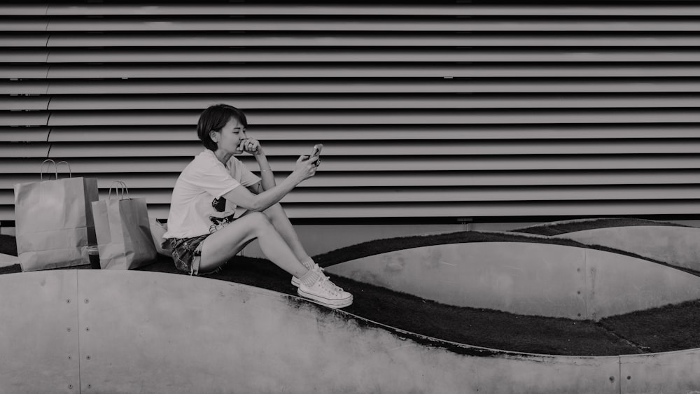 a person sitting on a ledge using a cell phone