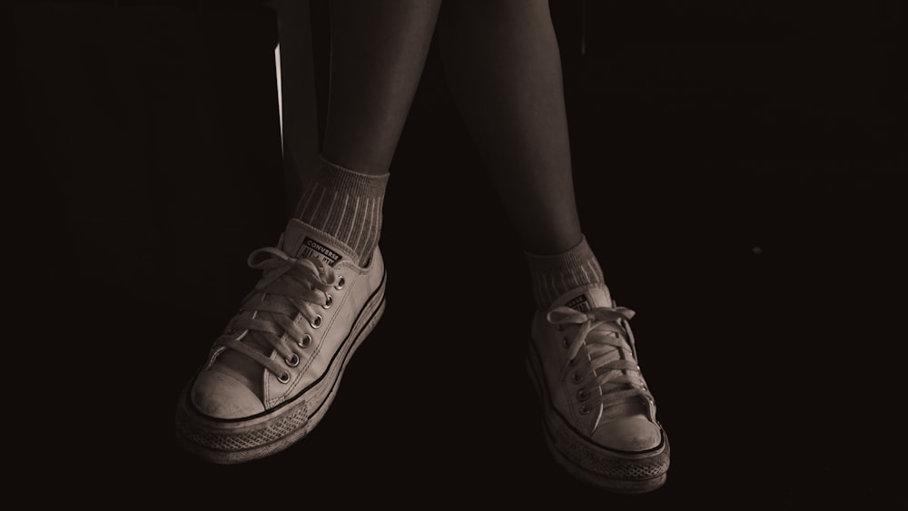 a black and white photo of a person's legs and shoes