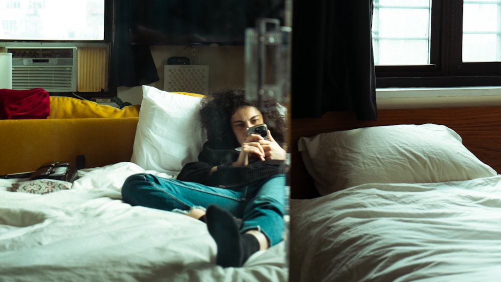 a woman sitting on a bed talking on a cell phone