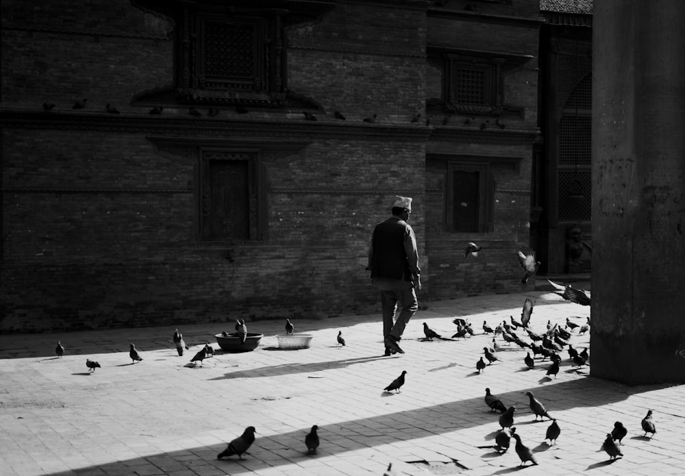 a black and white photo of a man surrounded by birds