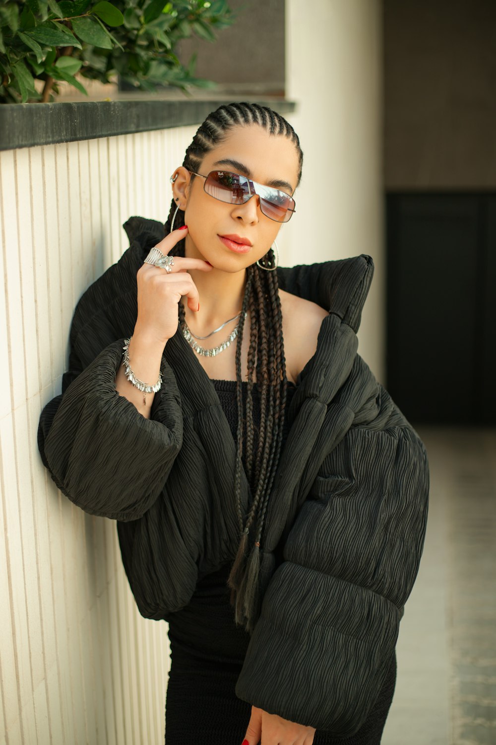 a woman wearing sunglasses leaning against a wall