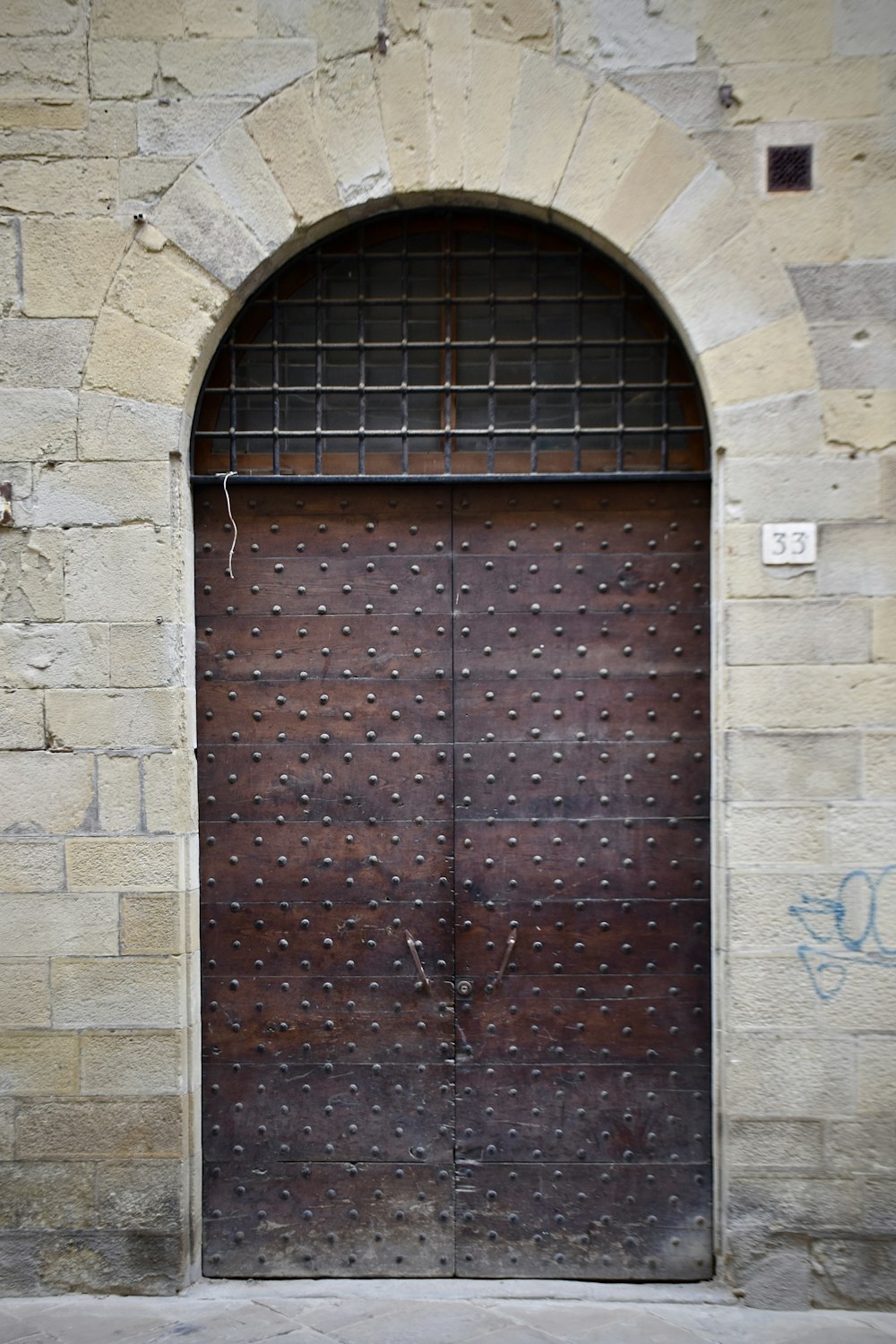a large wooden door with a brick wall behind it