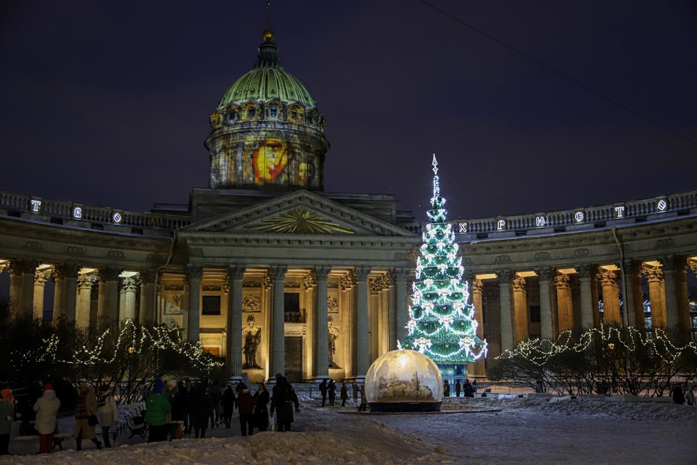 a lit christmas tree in front of a building