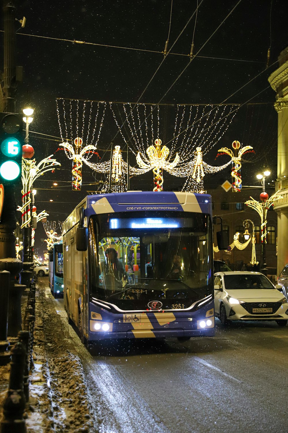 a bus driving down a street covered in christmas lights