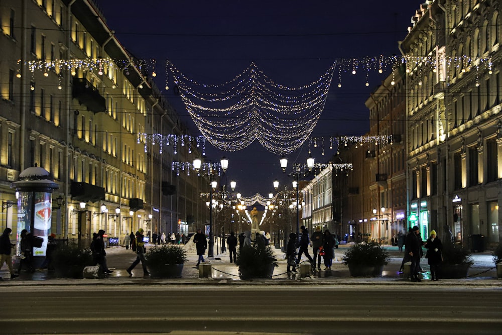 a group of people walking down a street at night