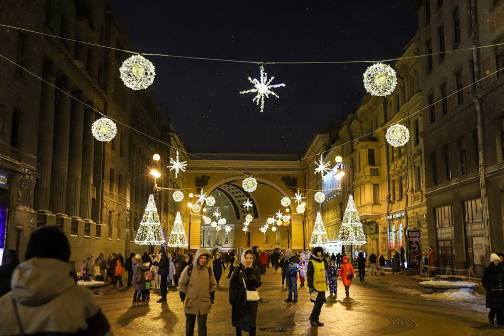 a group of people walking down a street covered in christmas lights